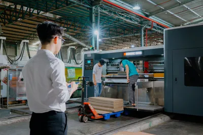 Công nhân vận hành máy in bế khổ lớn trong xưởng