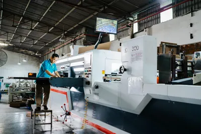 Máy in tờ rời khổ lớn đang chạy, công nhân đứng theo dõi bản in
