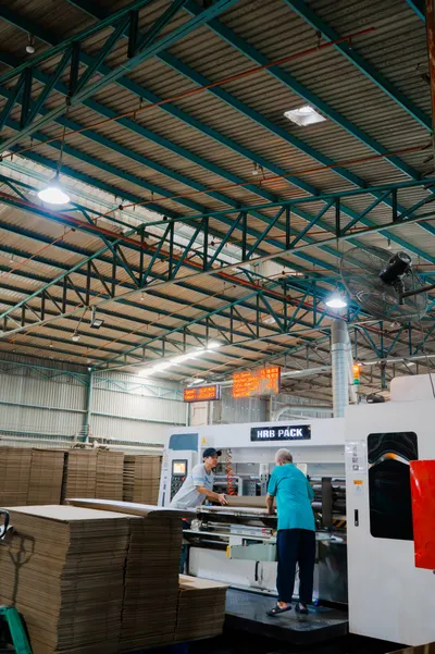 Công nhân thao tác với tấm carton lớn tại khu vực gia công
